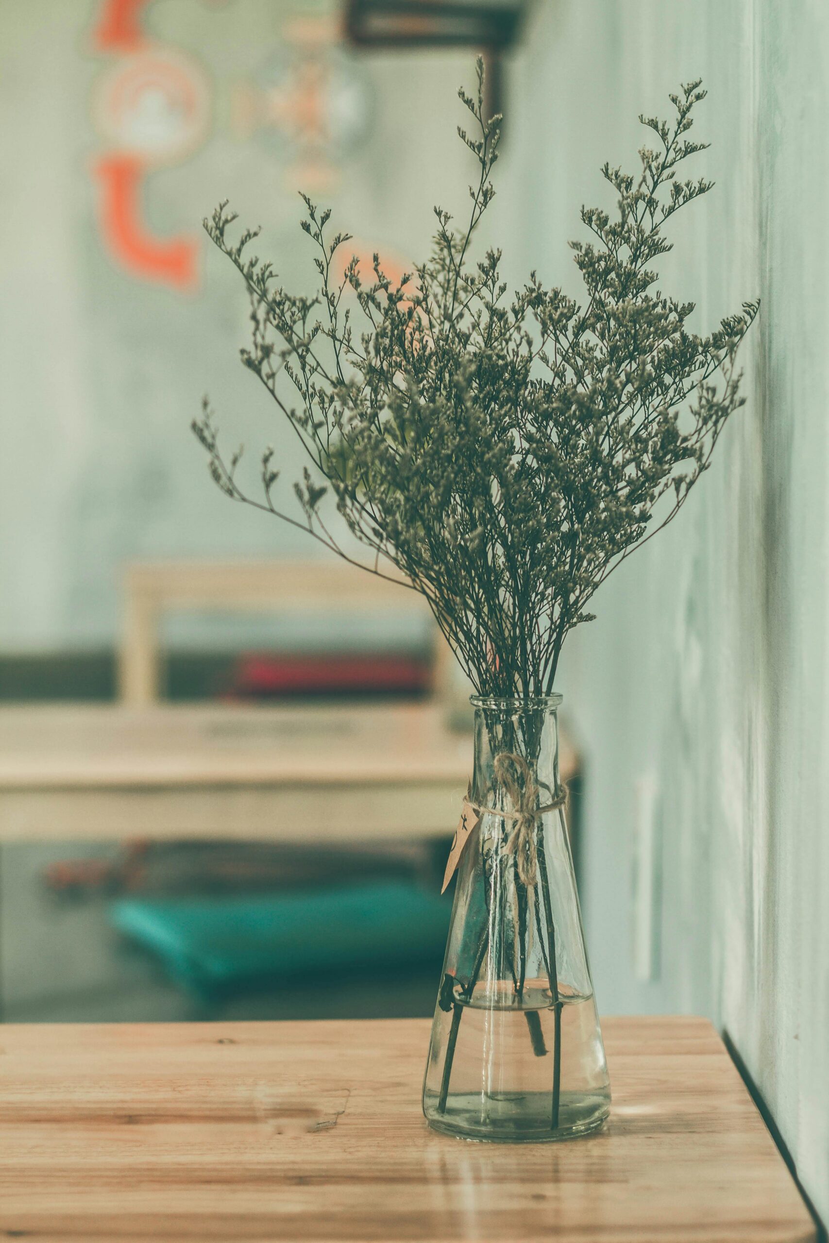 A minimalist interior featuring a vase of dried flowers on a wooden table in a tranquil setting.
